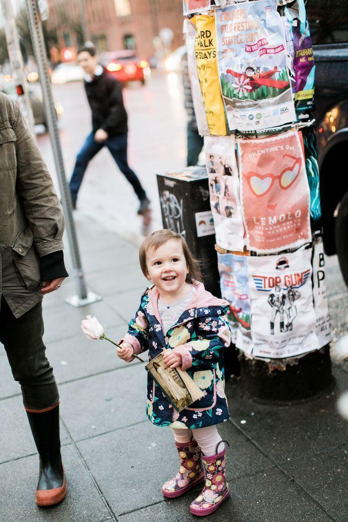 A garotinha sorrindo com a flor que ganhou de presente em mãos