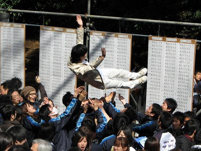 Aluno japonês sendo jogado para o alto pelos colegas por ter sido aprovado na universidade